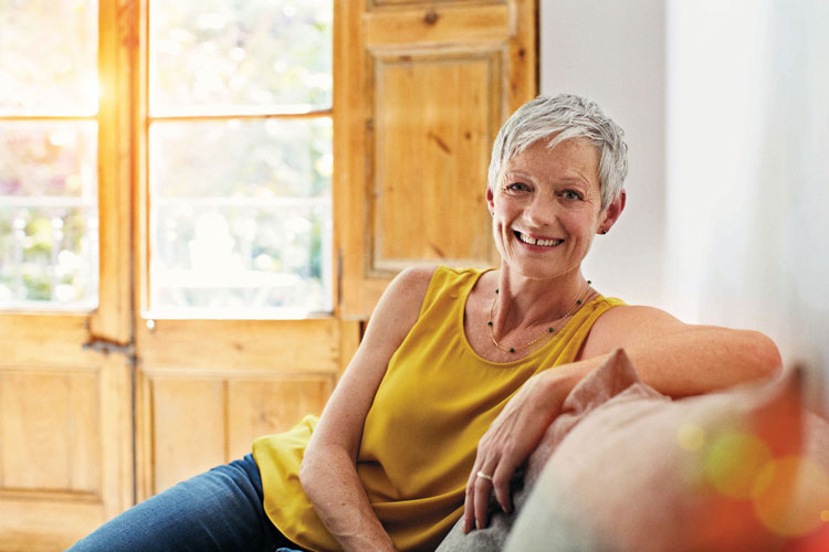 A lady, wearing a yellow top, sat on a sofa in the living room