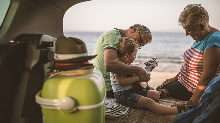 Grandparents smiling with granddaughter on beach